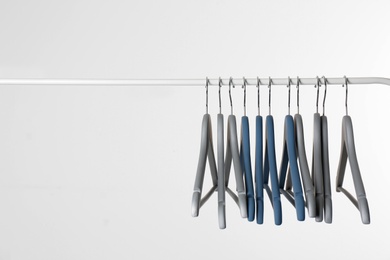 Photo of Metal rack with clothes hangers on white background, space for text