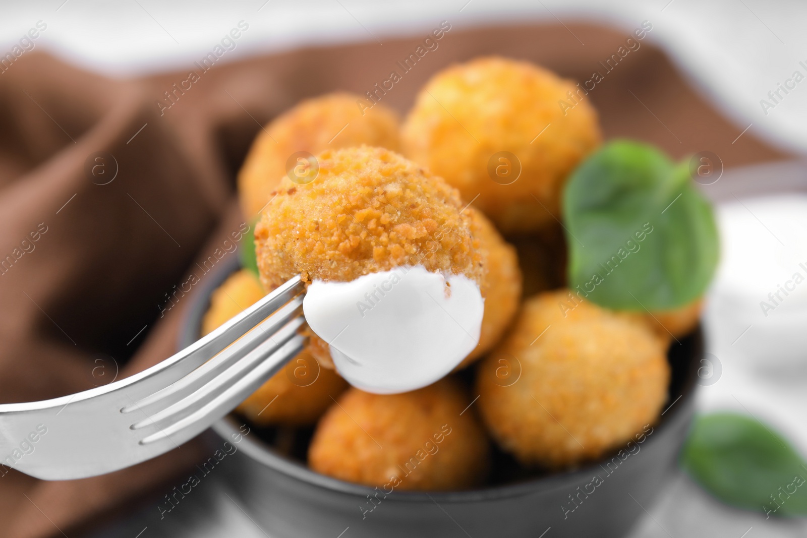 Photo of Taking delicious fried tofu ball with sauce from bowl, closeup