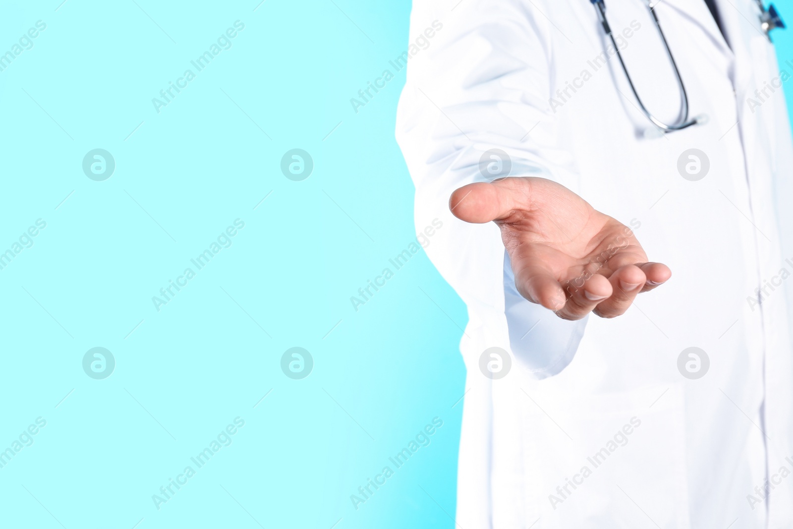 Photo of Male doctor offering helping hand on color background, closeup with space for text