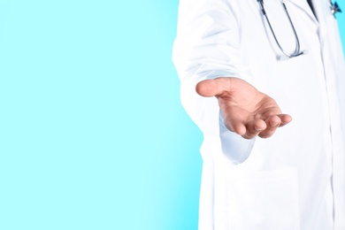 Photo of Male doctor offering helping hand on color background, closeup with space for text