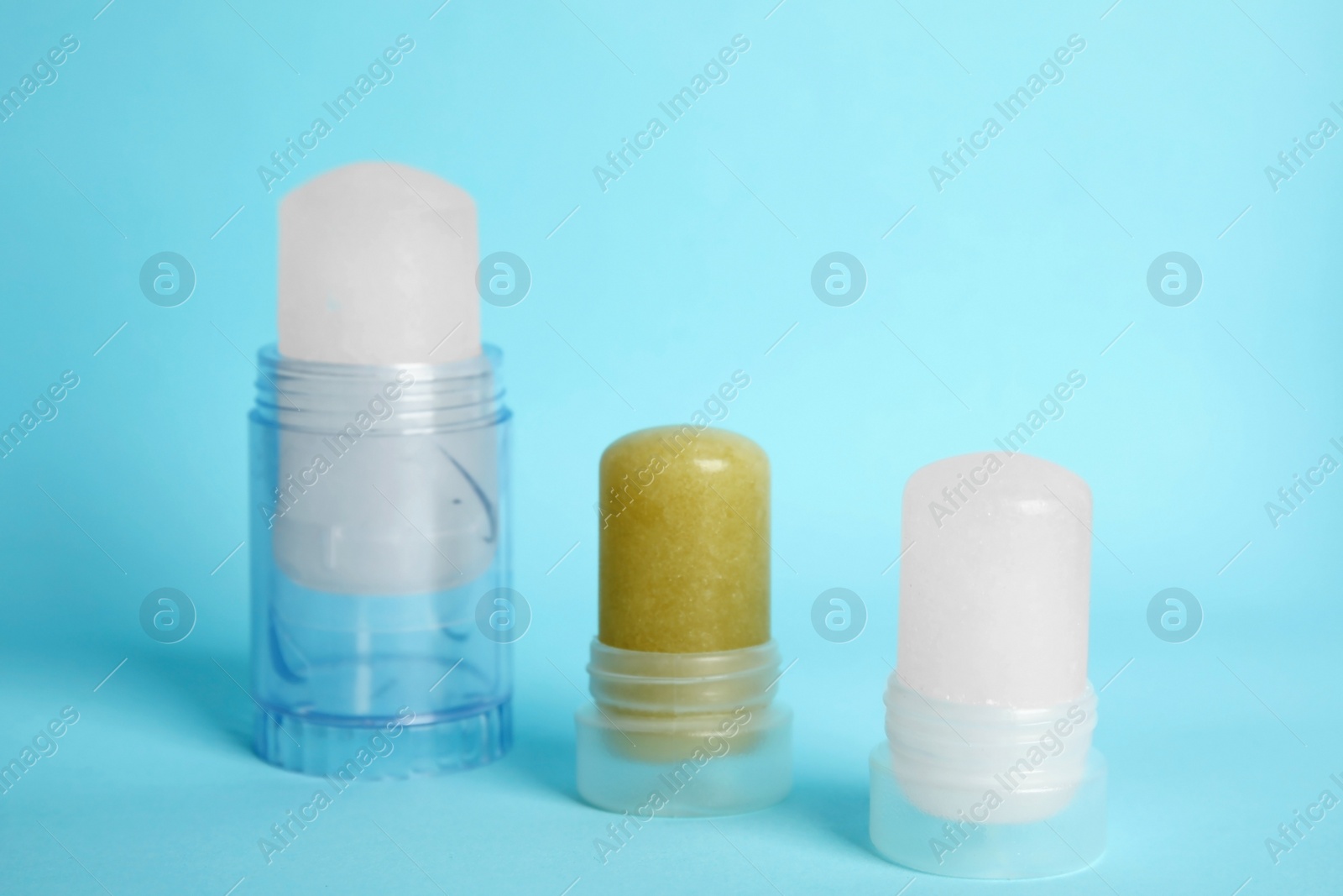 Photo of Natural crystal alum stick deodorants on light blue background