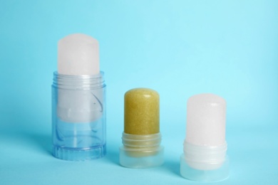 Photo of Natural crystal alum stick deodorants on light blue background