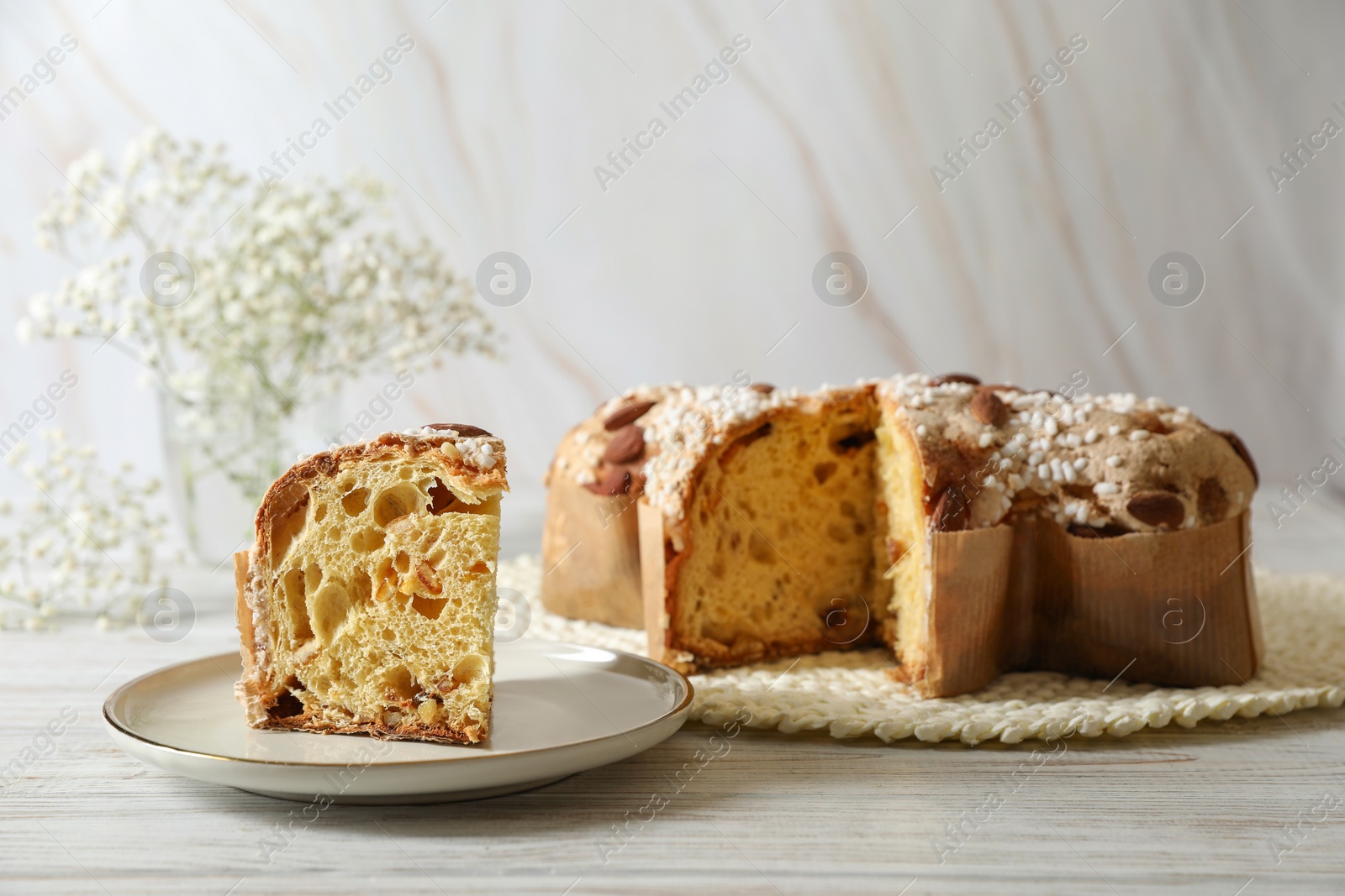 Photo of Delicious Italian Easter dove cake (traditional Colomba di Pasqua) on white wooden table, space for text