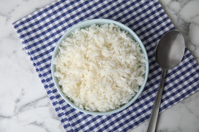 Photo of Bowl with tasty cooked rice on marble table, flat lay