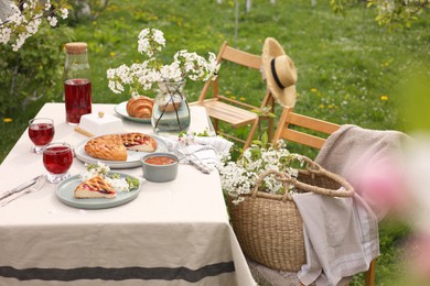 Photo of Stylish table setting with beautiful spring flowers, fruit drink and pie in garden