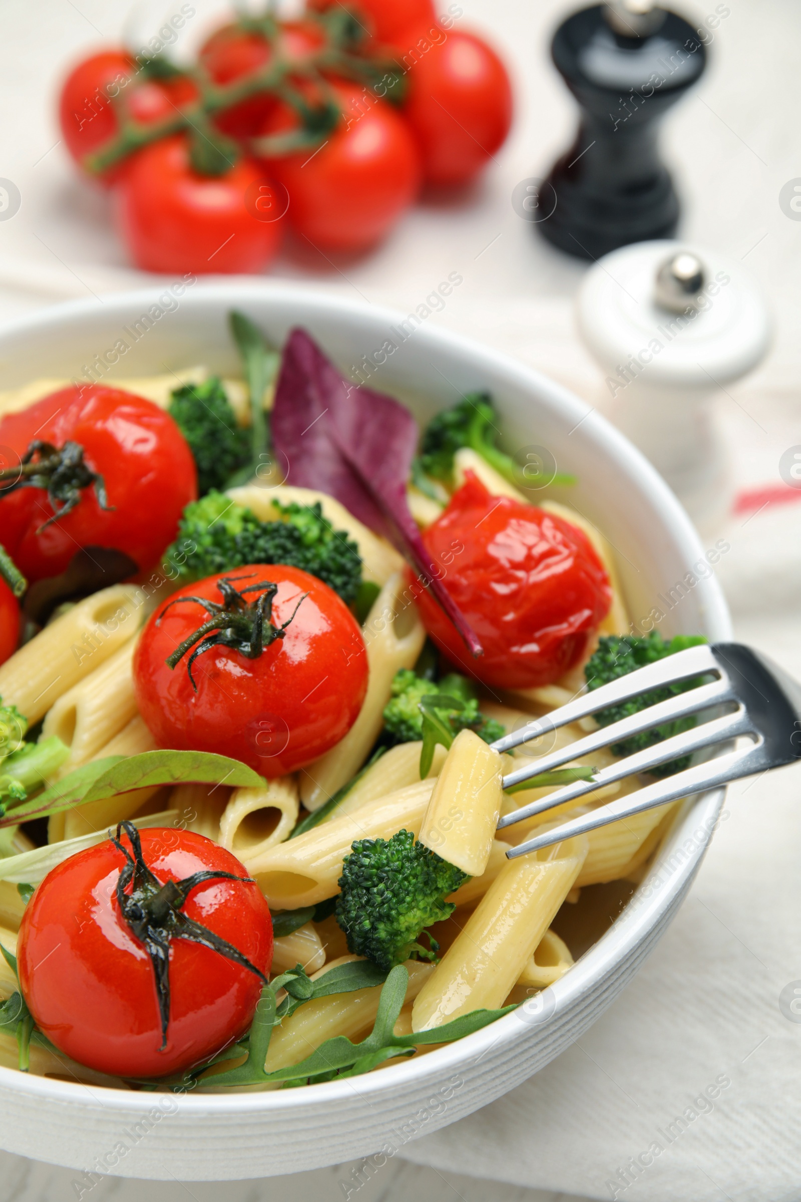 Photo of Bowl of delicious pasta with tomatoes, arugula and broccoli on white table, closeup
