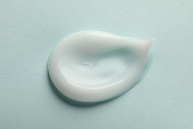 Sample of face cream on light blue background, top view