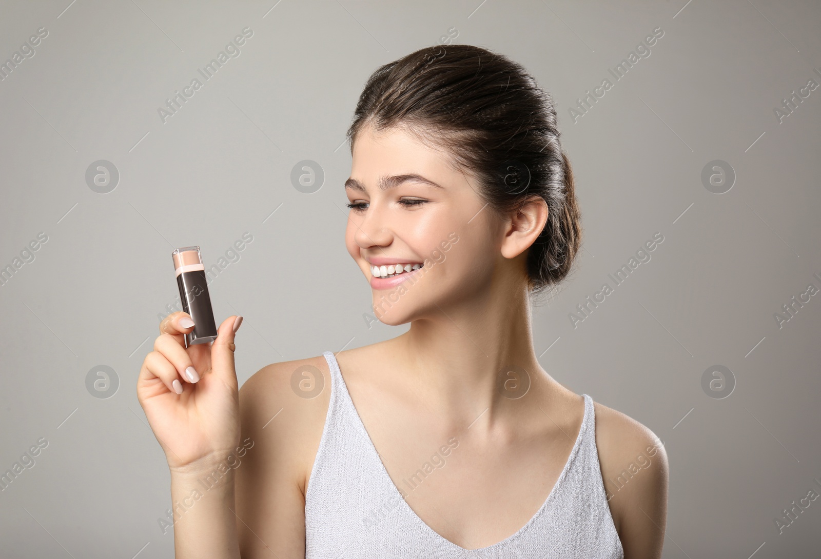 Photo of Beautiful girl with stick foundation on light grey background