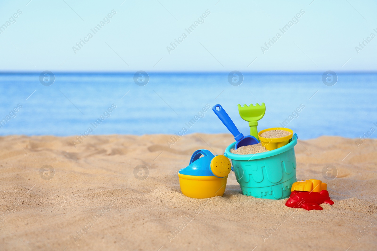 Photo of Set of plastic beach toys on sand near sea. Space for text