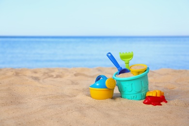 Photo of Set of plastic beach toys on sand near sea. Space for text