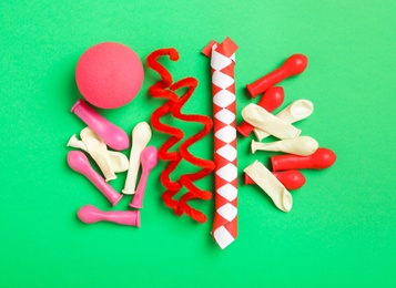 Photo of Different clown's accessories on green background, flat lay