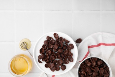 Photo of Breakfast cereal. Chocolate corn flakes and milk in bowl on white tiled table, flat lay. Space for text