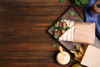 Photo of Delicious chicken shawarma and French fries served on wooden table, flat lay. Space for text