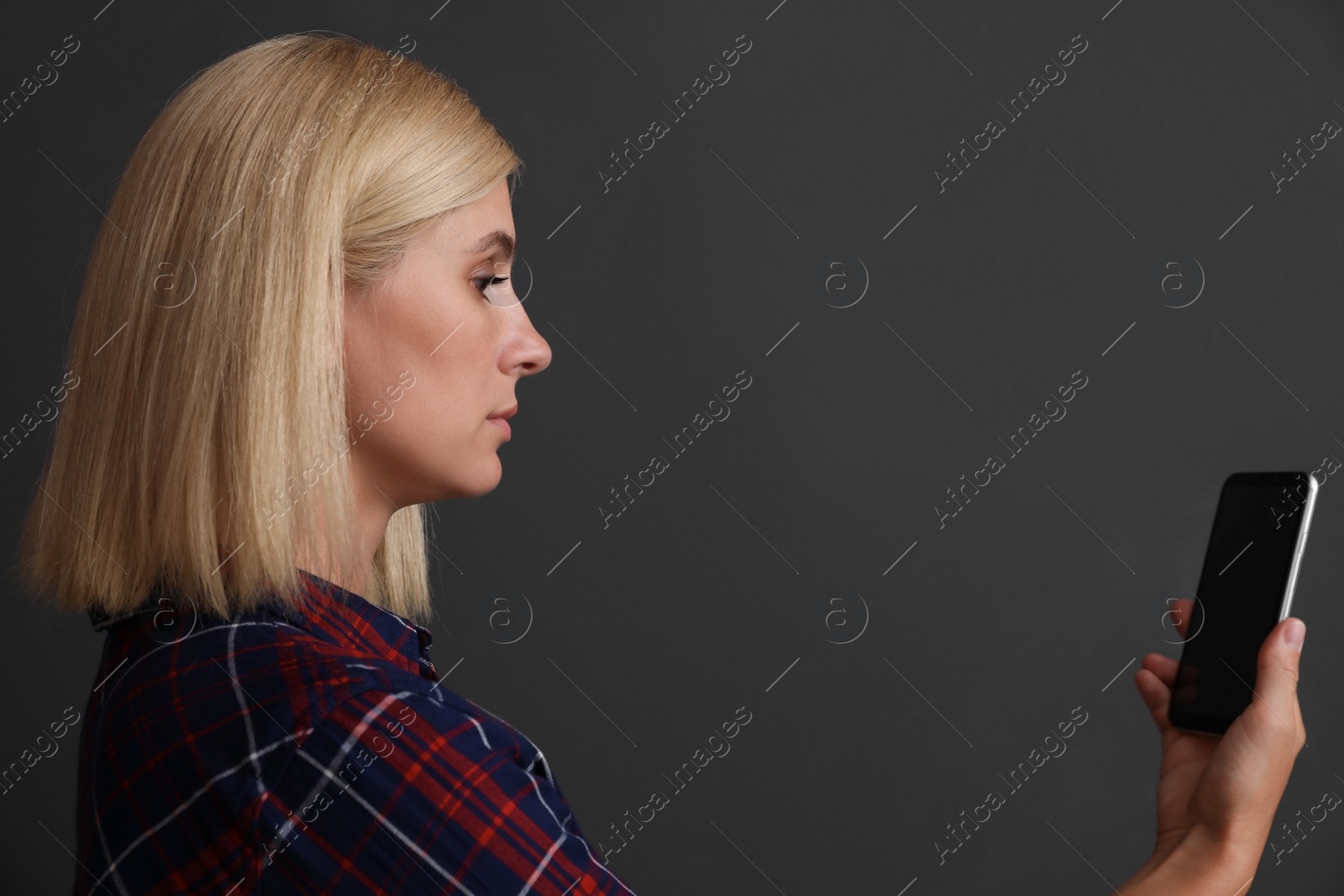 Photo of Woman using facial detection system of modern smartphone on grey background