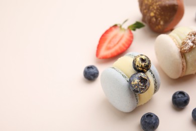 Delicious macarons and berries on beige table, closeup. Space for text