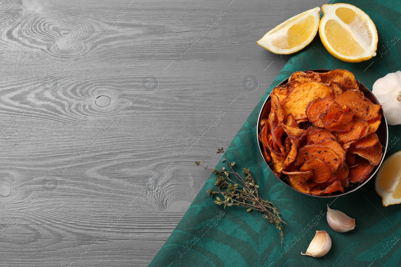 Photo of Flat lay composition with bowl of sweet potato chips and space for text on wooden table