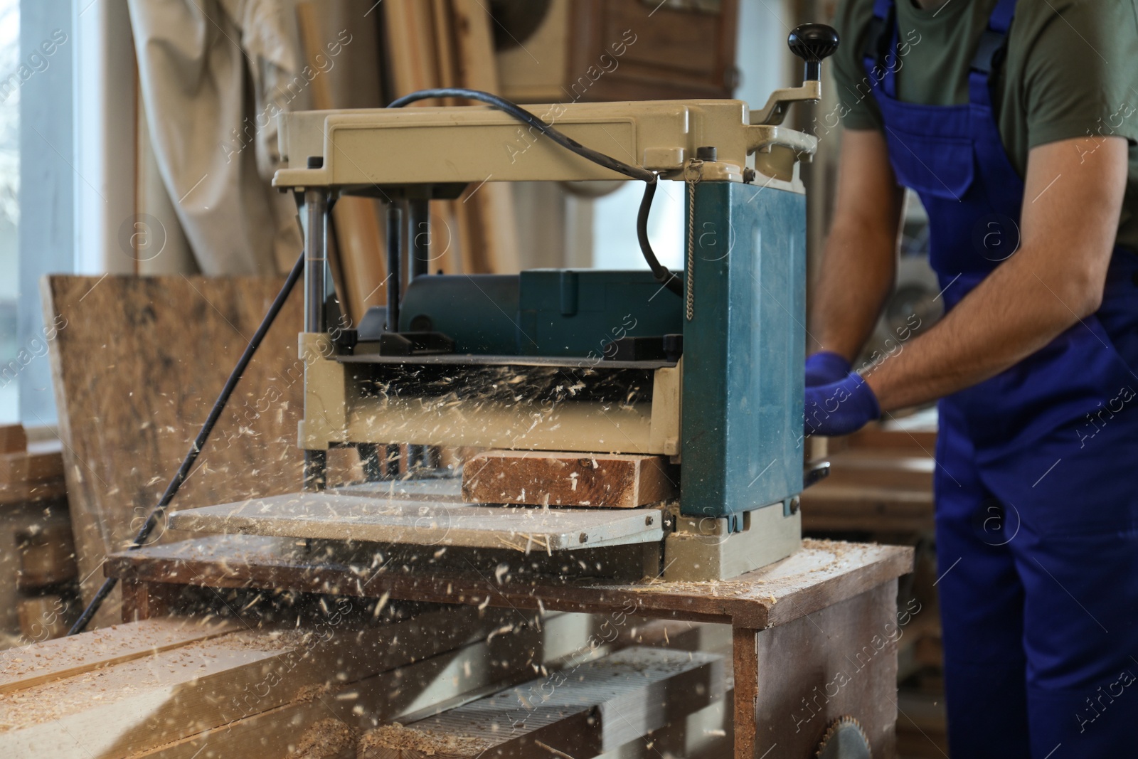 Photo of Professional carpenter working with grinding machine in shop, closeup