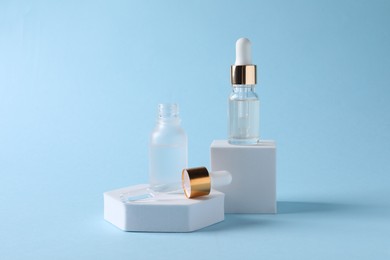 Photo of Presentation of bottles with cosmetic serums on light blue background