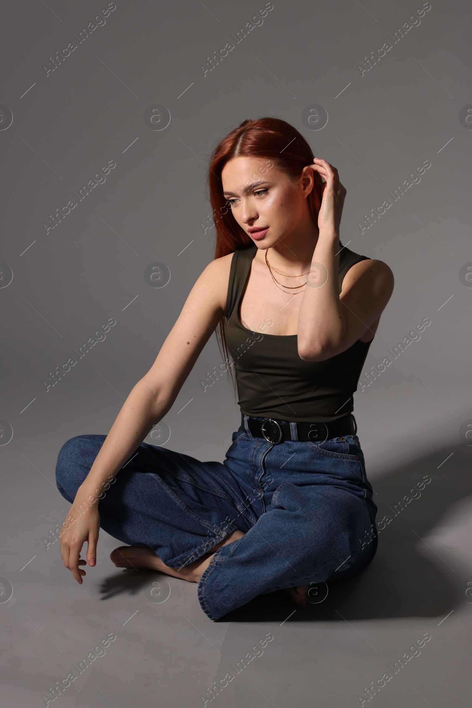 Photo of Beautiful young woman sitting on gray background