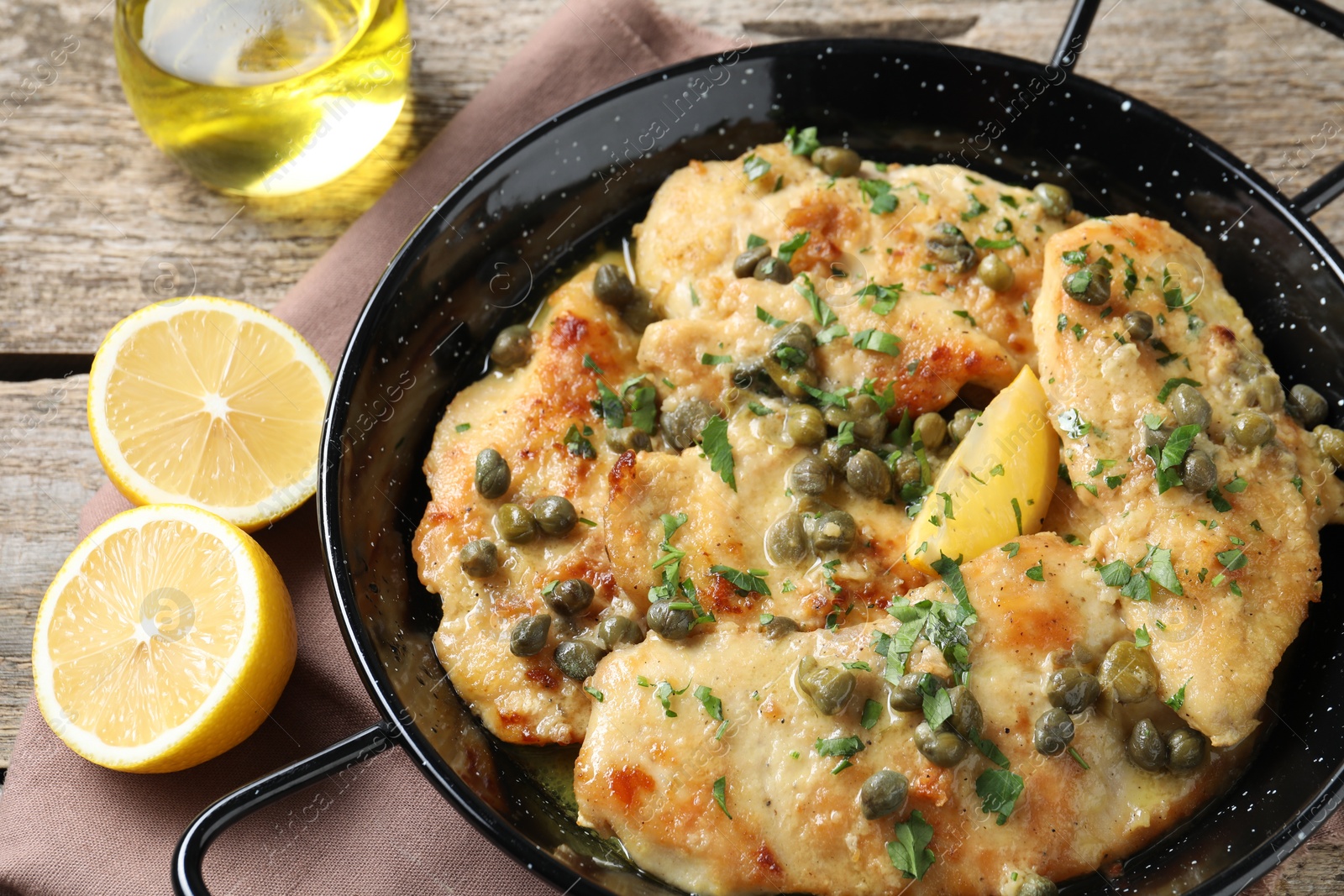 Photo of Delicious chicken piccata with herbs on wooden table