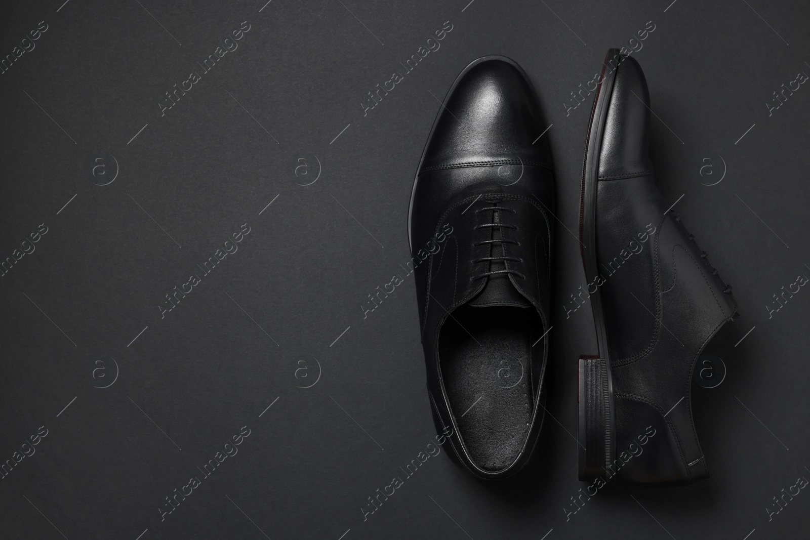 Photo of Pair of leather men shoes on black background, top view. Space for text