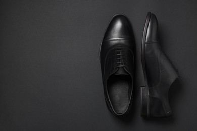 Photo of Pair of leather men shoes on black background, top view. Space for text