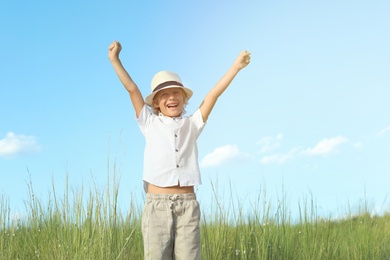 Photo of Cute little boy wearing stylish hat outdoors. Child spending time in nature