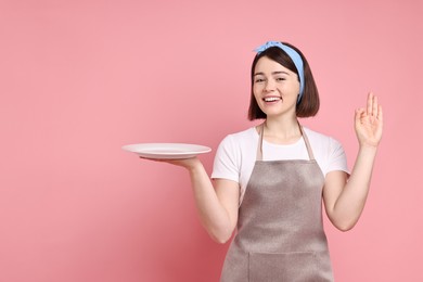 Photo of Happy confectioner with plate showing ok gesture on pink background, space for text