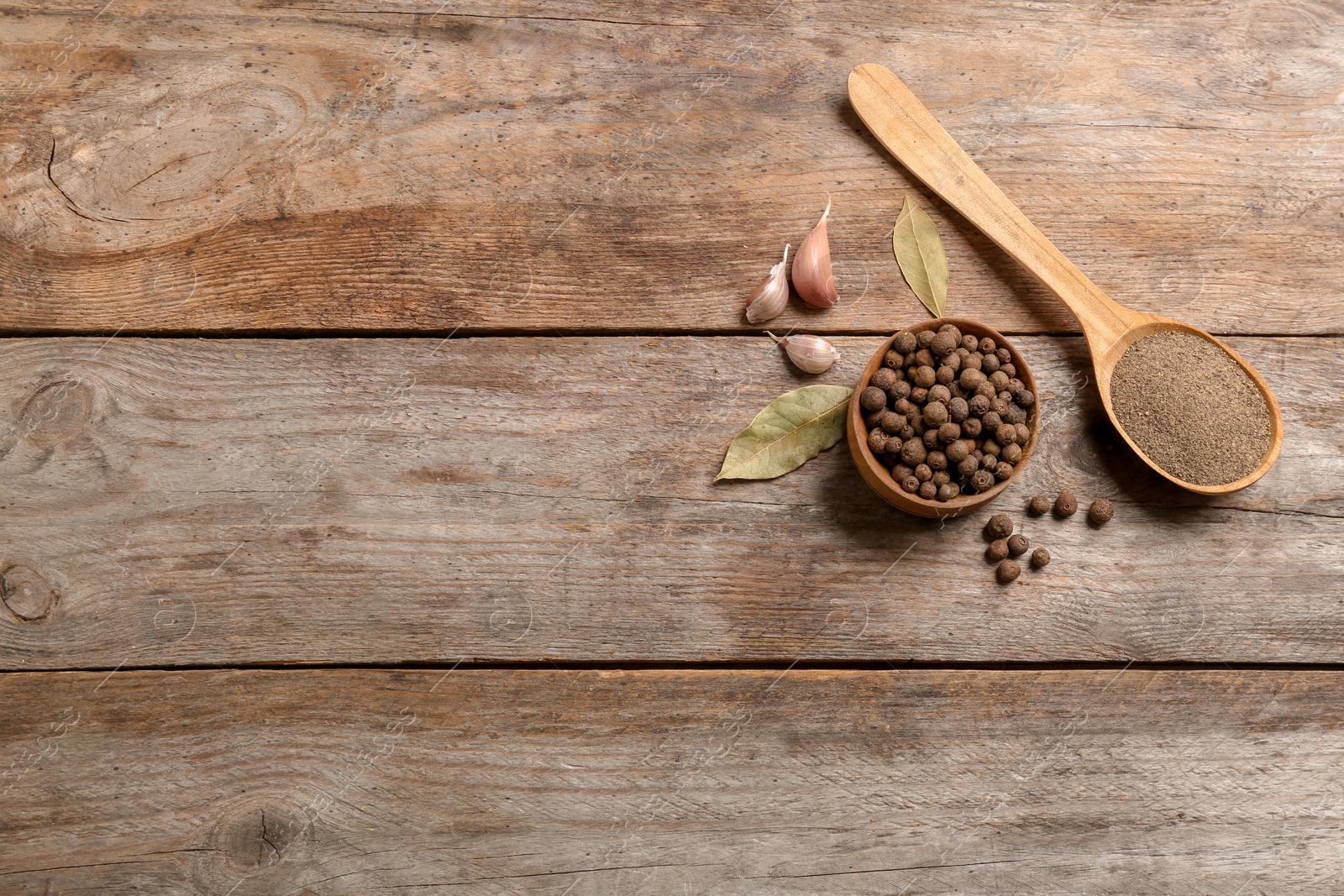 Photo of Flat lay composition with allspice peppercorns in bowl and space for text on wooden background