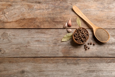 Photo of Flat lay composition with allspice peppercorns in bowl and space for text on wooden background