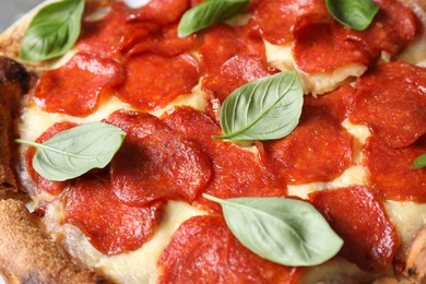 Tasty pepperoni pizza with basil as background, closeup