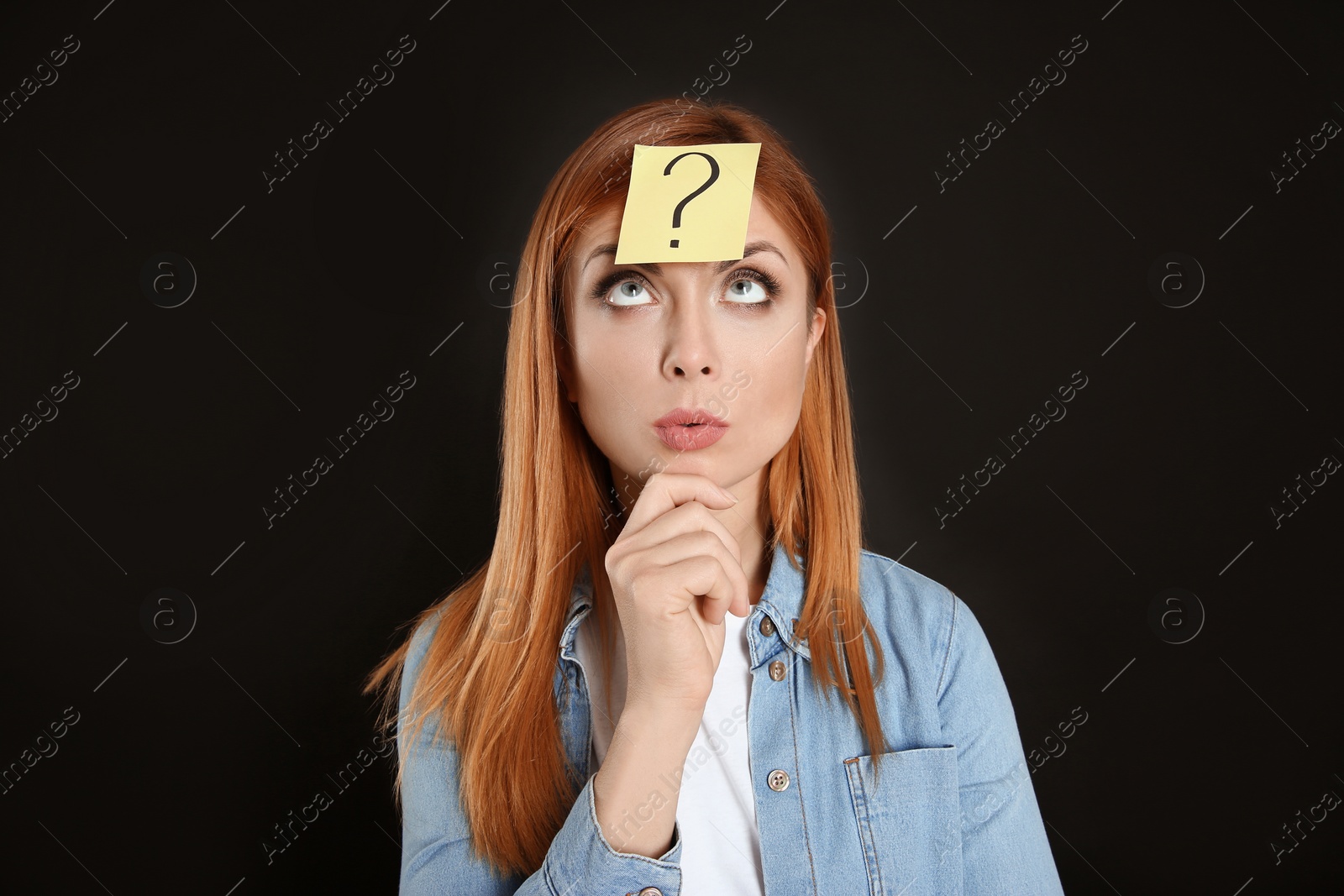 Photo of Pensive woman with question mark sticker on forehead against black background