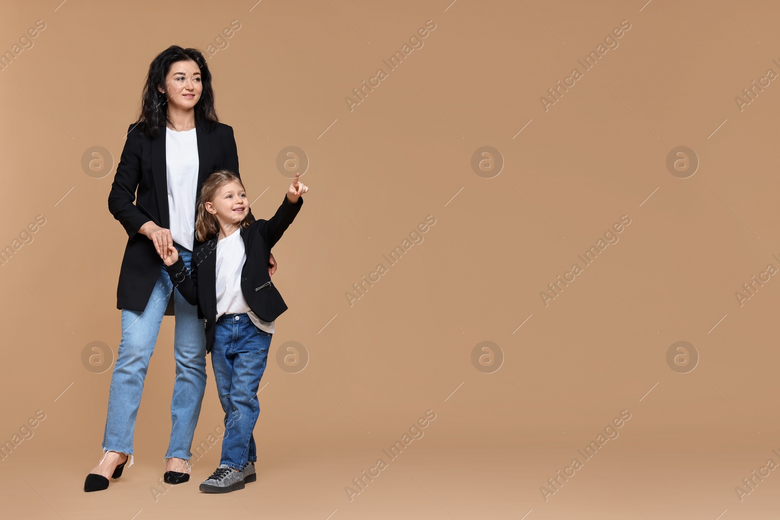 Photo of Beautiful mother with little daughter on beige background. Space for text