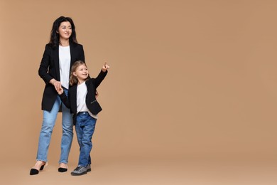 Photo of Beautiful mother with little daughter on beige background. Space for text