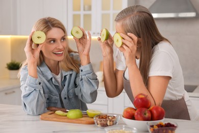 Happy mature mother and her daughter having fun in kitchen