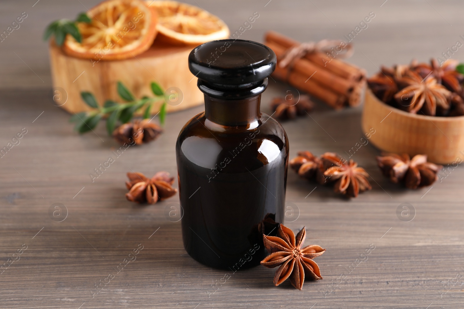 Photo of Anise essential oil and spice on wooden table