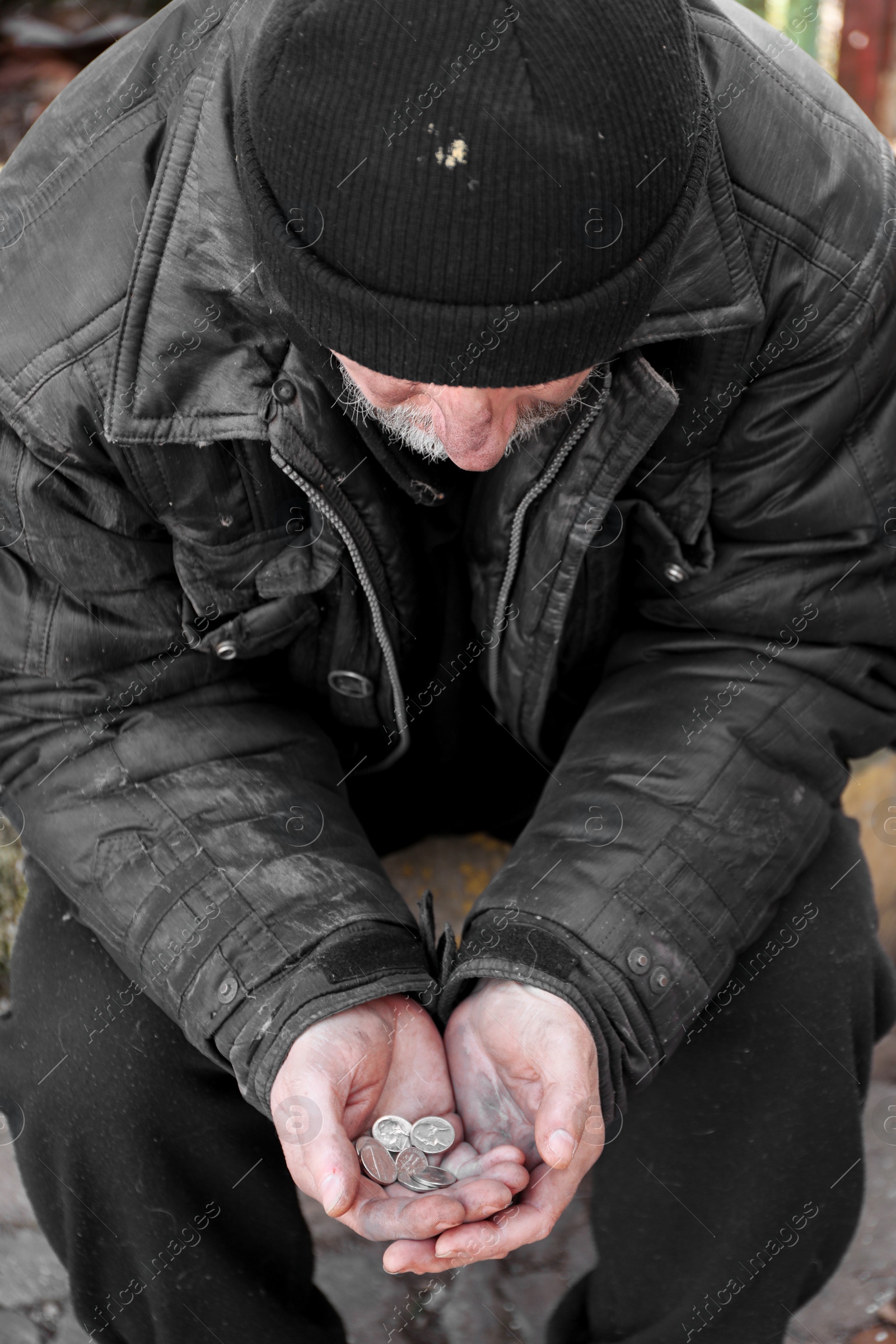 Photo of Poor homeless senior man holding coins outdoors