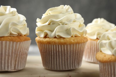 Photo of Tasty cupcakes with vanilla cream on table, closeup