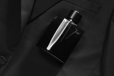 Photo of Luxury men's perfume in bottle on black jacket, top view