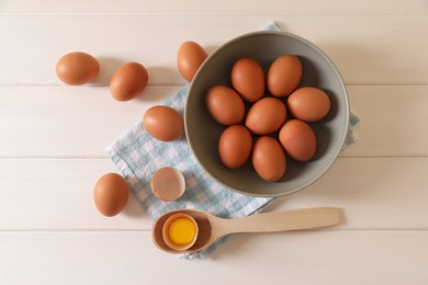 Photo of Cracked and whole chicken eggs on white wooden table, flat lay