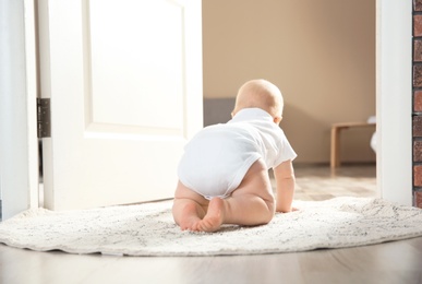 Photo of Cute little baby crawling on rug indoors