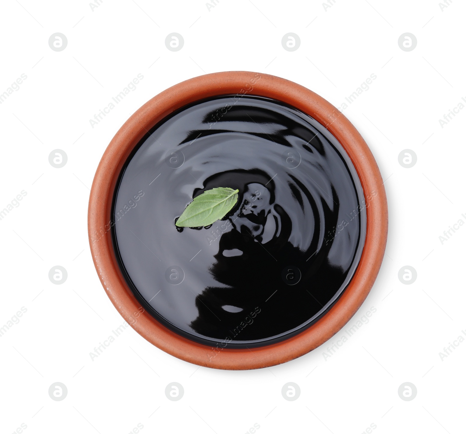 Photo of Balsamic glaze with basil leaf in bowl isolated on white, top view