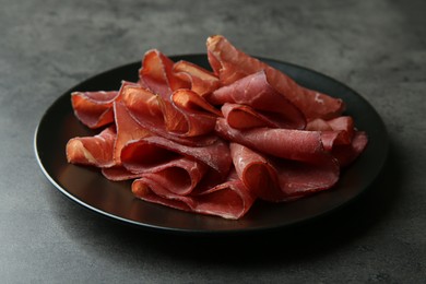 Photo of Plate with tasty bresaola on grey table