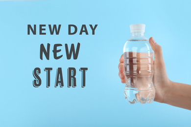 Inspirational text New Day New Start and woman holding bottle of water on light blue background