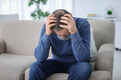 Mature man suffering from headache at home