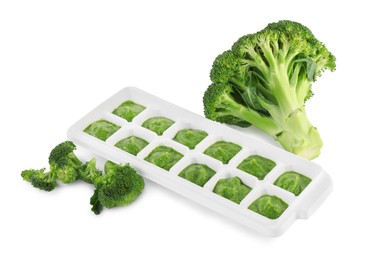 Photo of Broccoli puree in ice cube tray and ingredients on white background. Ready for freezing