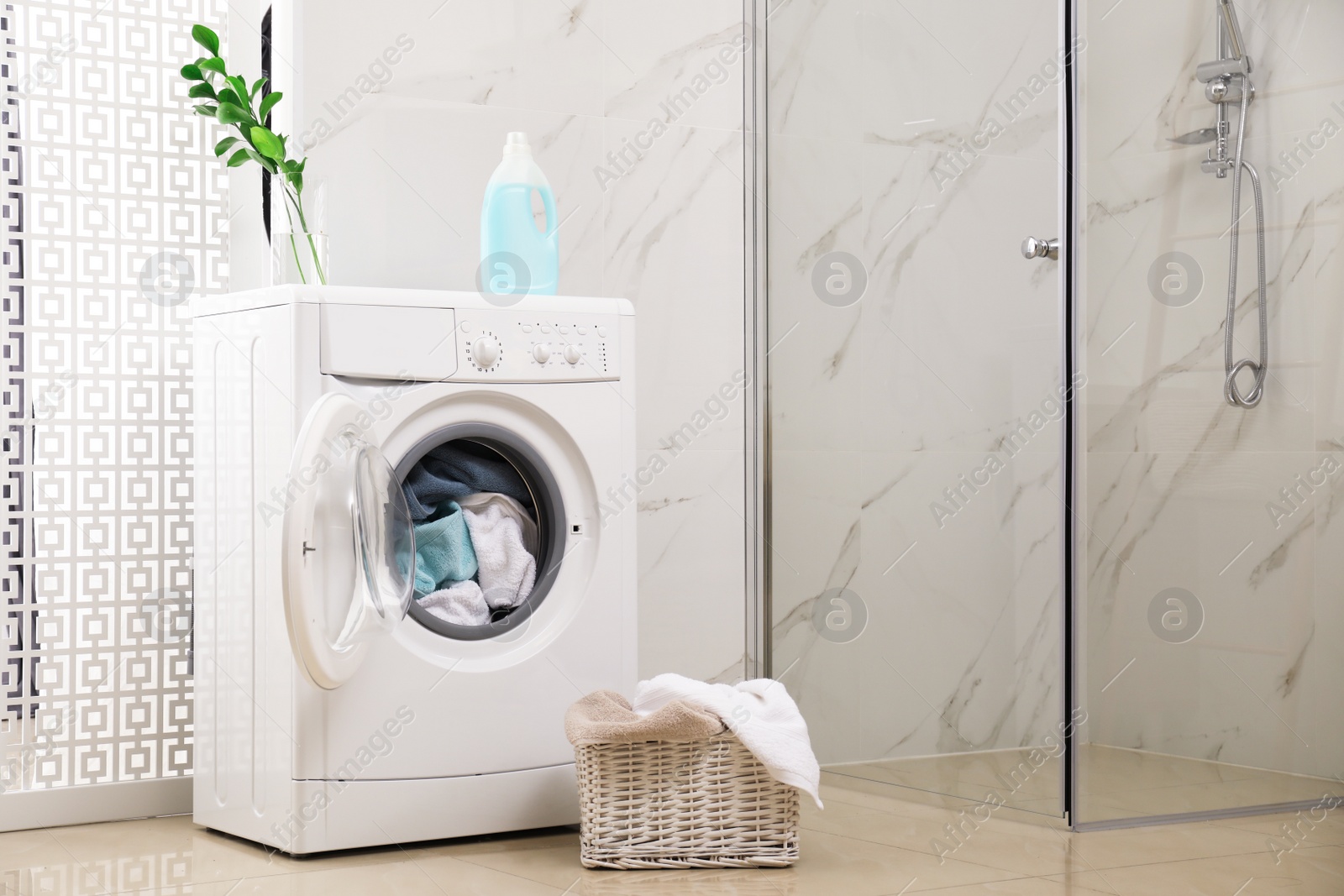 Photo of Modern washing machine with towels in bathroom