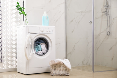 Photo of Modern washing machine with towels in bathroom