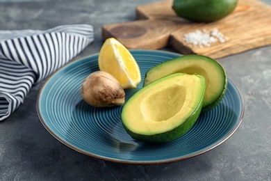 Photo of Plate with ripe avocado and lemon on table