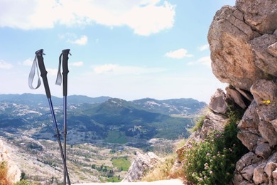 Image of Trekking poles and beautiful view of mountains on sunny day. Space for text